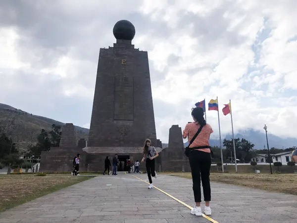 Person jumping on the Equator Line by the Middle of the World Monument